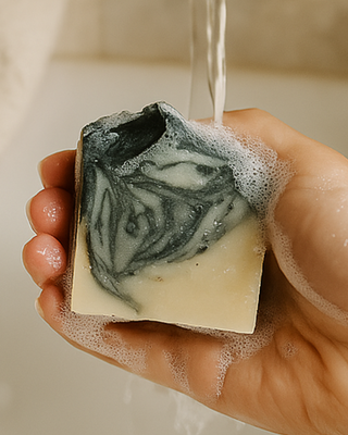 Charcoal Cleanse bar producing creamy lather in hands